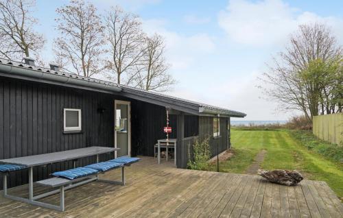 a black house with a bench on a wooden deck at 3 Bedroom Lovely Home In Bjert in Binderup Strand