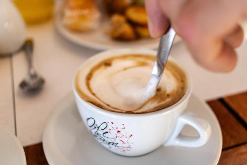 a person stirring a cup of coffee with a spoon at Corte Mercurio B&B in Ugento