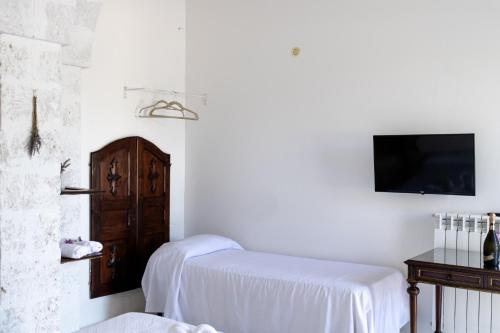 a white room with a bed and a tv at Corte Mercurio B&B in Ugento