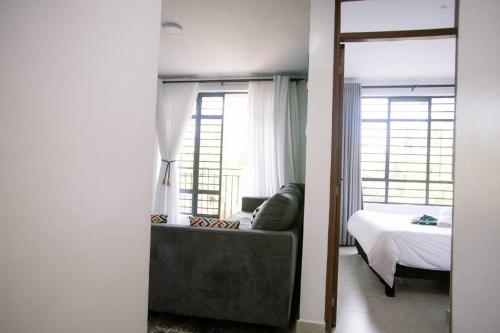 a bedroom with a bed and a couch and a mirror at 1 bedroom cosy apartment in Nairobi, Kitsuru in Nairobi