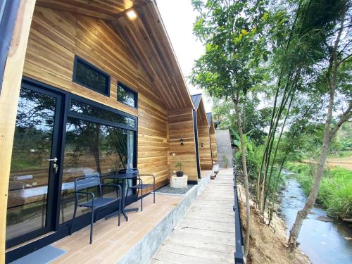 a home with a deck with a table and chairs at Shine River in Ciwidey