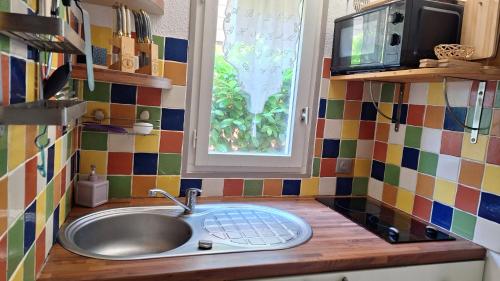 une cuisine avec un évier et une fenêtre dans l'établissement Détente et Nature Maisonnette Conviviale pour 6 Personnes dans un Village de vacances, à Gujan-Mestras