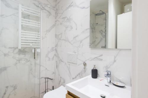 une salle de bain blanche avec un lavabo et un miroir dans l'établissement Margot, à Beausoleil