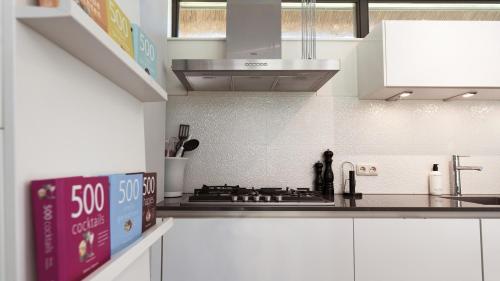 a kitchen with white cabinets and a stove top oven at Dutchen Villapark Mooi Schoorl in Schoorl