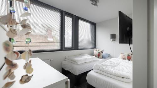 a room with two beds and a tv and windows at Dutchen Villapark Mooi Schoorl in Schoorl