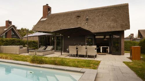 a house with a swimming pool next to a house at Dutchen Villapark Mooi Schoorl in Schoorl