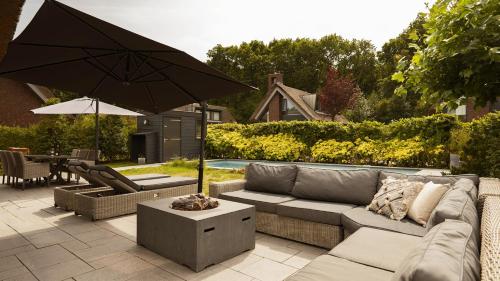 a patio with a couch and an umbrella at Dutchen Villapark Mooi Schoorl in Schoorl