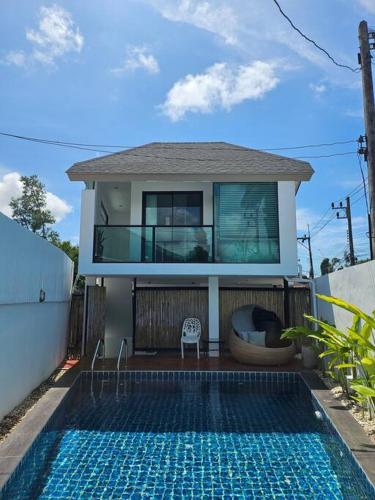 a house with a swimming pool in front of a house at Happy Villa in Choengtalay in Laguna Phuket