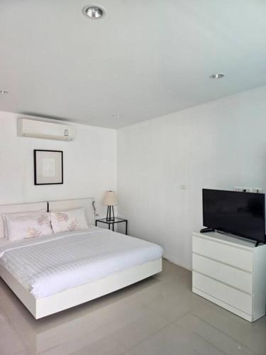 a white bedroom with a bed and a flat screen tv at Happy Villa in Choengtalay in Laguna Phuket