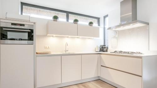 a white kitchen with white cabinets and a window at Dutchen Villapark Mooi Schoorl in Schoorl