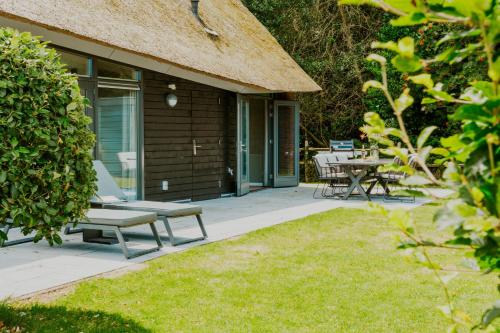 a patio with chairs and tables on a house at Dutchen Villapark Mooi Schoorl in Schoorl