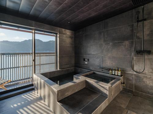 a bathroom with a large tub and a large window at Funaya Kura 藏 in Ine