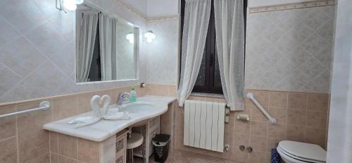 Un baño con lavabo, inodoro y espejo. en Villa Pierpaola, en Castelsardo