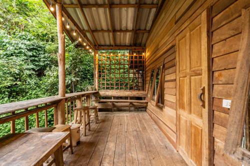 a porch of a cabin with wooden tables and benches at ไชยพล โฮมสเตย์ หมู่บ้านแม่กำปอง in Ban Pok Nai