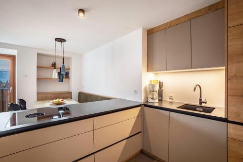 a kitchen with white cabinets and black counter tops at Residence Linderhof in Naz-Sciaves