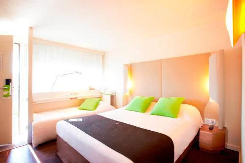 a hotel room with two beds with green pillows at Hotel Campanile Besançon Nord Ecole Valentin in Besançon
