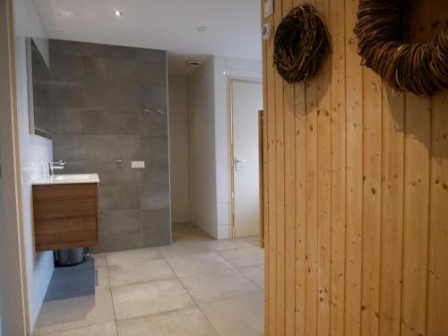 a bathroom with a sink and a wooden wall at Villa Buiten 130 met Sauna in Callantsoog