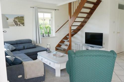 a living room with a blue couch and a staircase at Buitenplaats Villa Deluxe in Callantsoog
