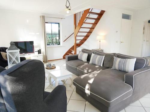 a living room with couches and a staircase at Buitenplaats Villa Deluxe in Callantsoog