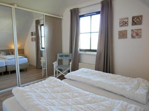 a hotel room with two beds and a mirror at Buitenplaats Villa Deluxe in Callantsoog