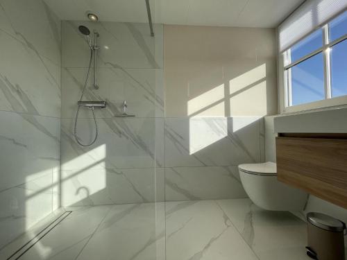 a white bathroom with a shower and a toilet at Villa Lighthouse in Callantsoog
