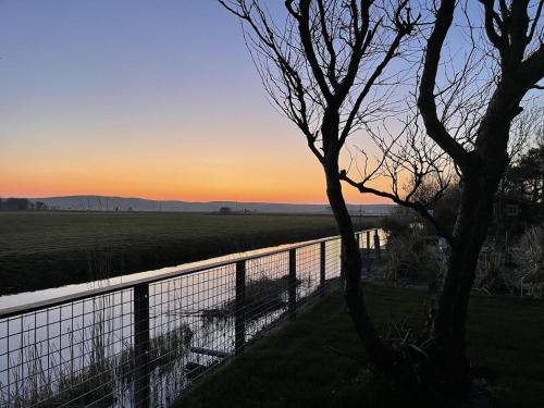a fence in front of a field with the sunset at Villa Lighthouse in Callantsoog