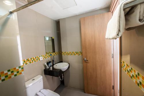 a small bathroom with a toilet and a sink at Kyriad Haka Makassar in Makassar