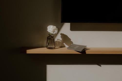 a vase of flowers and a book on a shelf at Hotel Auerhahn in Schluchsee