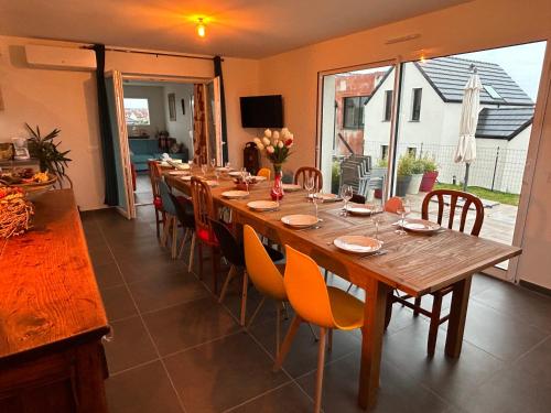 einen langen Holztisch und Stühle in einem Zimmer in der Unterkunft En famille ou amis avec la mer in Équihen-Plage