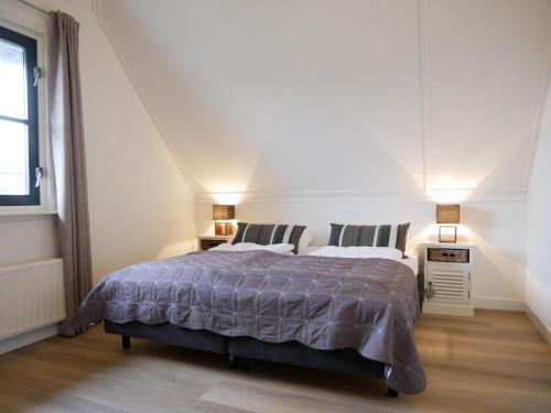 a white bedroom with a bed and two lamps at Buitenplaats 108 in Callantsoog