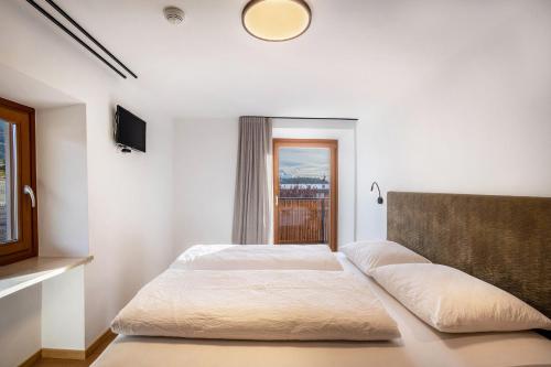 a white bedroom with a bed and a window at Residence Linderhof in Naz-Sciaves