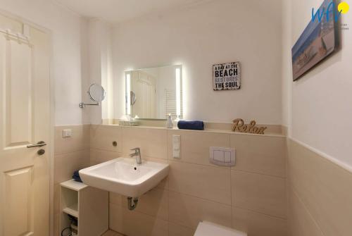 a white bathroom with a sink and a mirror at Bootshaus in den Duenen - 5 - "Ferienwohnung Duenengefluester" in Wangerooge