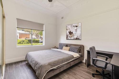 a bedroom with a bed and a desk and a window at Spacious 3-Bedroom Family Home in Concord's Heart! in Sydney