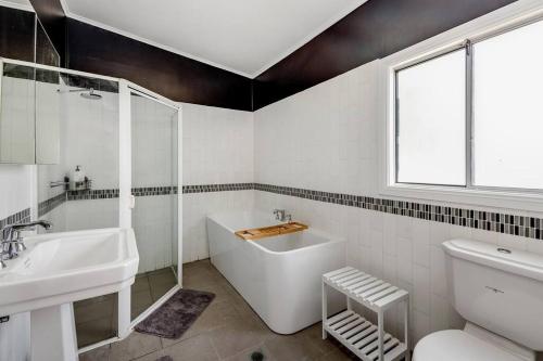 a white bathroom with a tub and a sink at Spacious 3-Bedroom Family Home in Concord's Heart! in Sydney