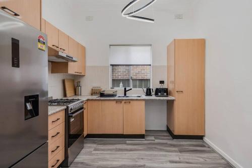 a kitchen with wooden cabinets and a stainless steel refrigerator at Spacious 3-Bedroom Family Home in Concord's Heart! in Sydney