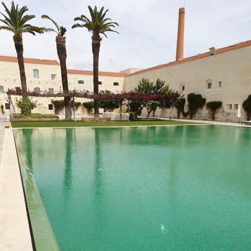 a large swimming pool with palm trees in front of a building at Apartamento Convento das Bernadas Tavira in Tavira