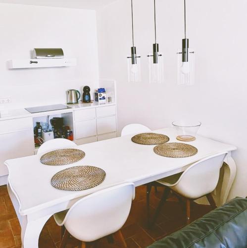 a white table with white chairs and a white kitchen at Apartamento Convento das Bernadas Tavira in Tavira