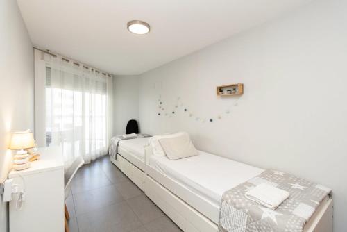 a white bedroom with two beds and a window at GuestReady - Lovely home close to Platja del Puig in El Puig