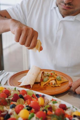 a man eating a slice of pizza next to a plate of food at Hotel Roger de Flor by Seleqtta in Lloret de Mar