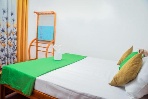 a bed with a green blanket and a mirror on it at Nethu Villa Dodanduwa in Dodanduwa