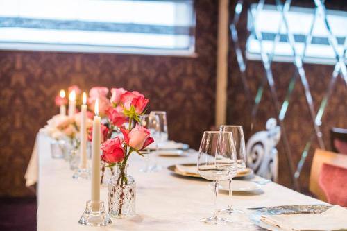 a table with candles and roses in vases and glasses at Simfonia Boutique Hotel in Râmnicu Vâlcea