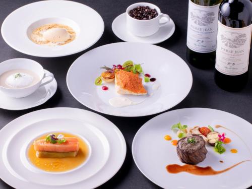 a table with white plates of food and bottles of wine at Hotel New Otani Saga in Saga