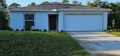 a blue house with a garage and a driveway at Cozy house with a Heated Swim spa in Port Charlotte