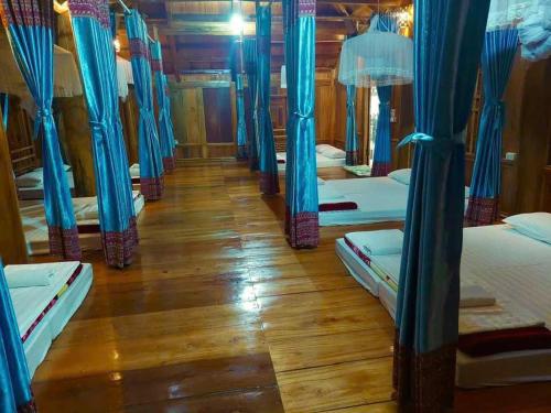 a row of beds in a room with blue curtains at Hiếu Hương Homestay in Lũng Tiềm