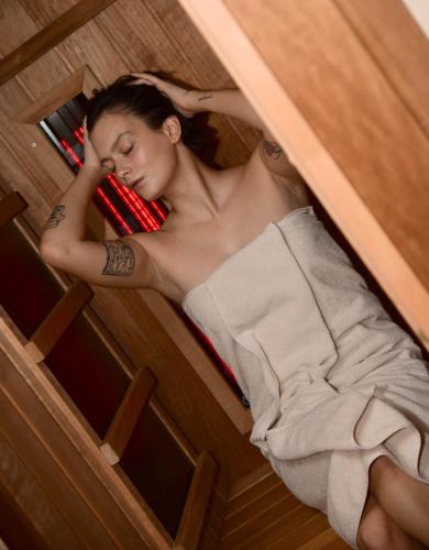 a woman laying on a bed while holding a cell phone at 5 Sunca in Kašina