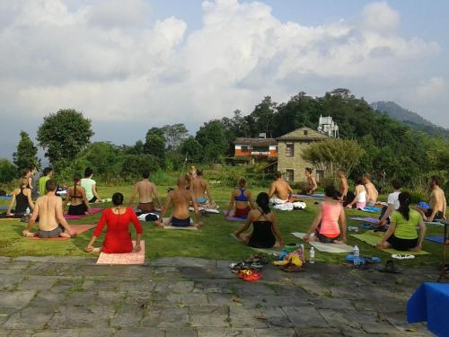a group of people sitting in the grass doing yoga at Himalayan Deurali Resort in Pokhara