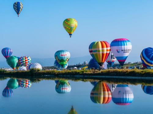a bunch of hot air balloons flying over the water at Hotel New Otani Saga in Saga