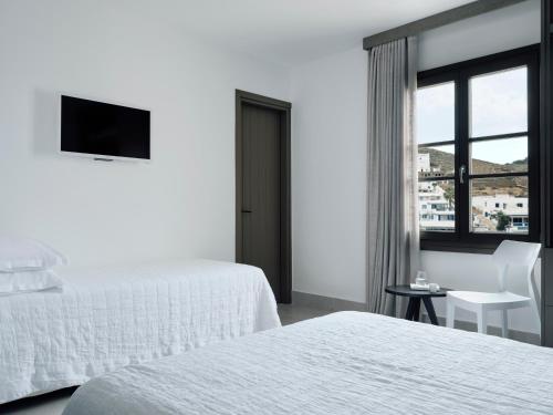 a white hotel room with two beds and a window at Acteon Hotel in Ios Chora