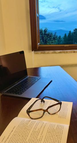 a book and glasses on a table with a laptop at Agriturismo Colle Vento in Corciano