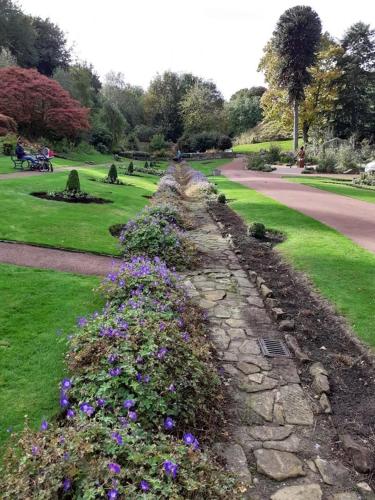 a stone path in a park with purple flowers at Castle View Bed and Breakfast in Morpeth